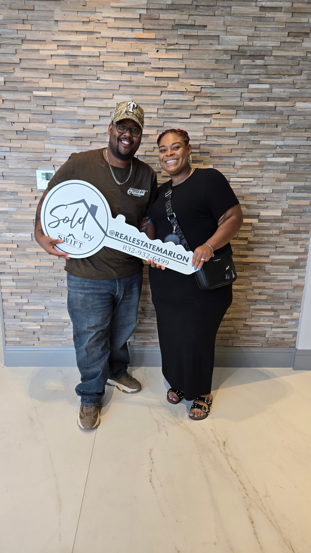 Marlon Wilson with clients posing with a sold key sign after closing on a home.