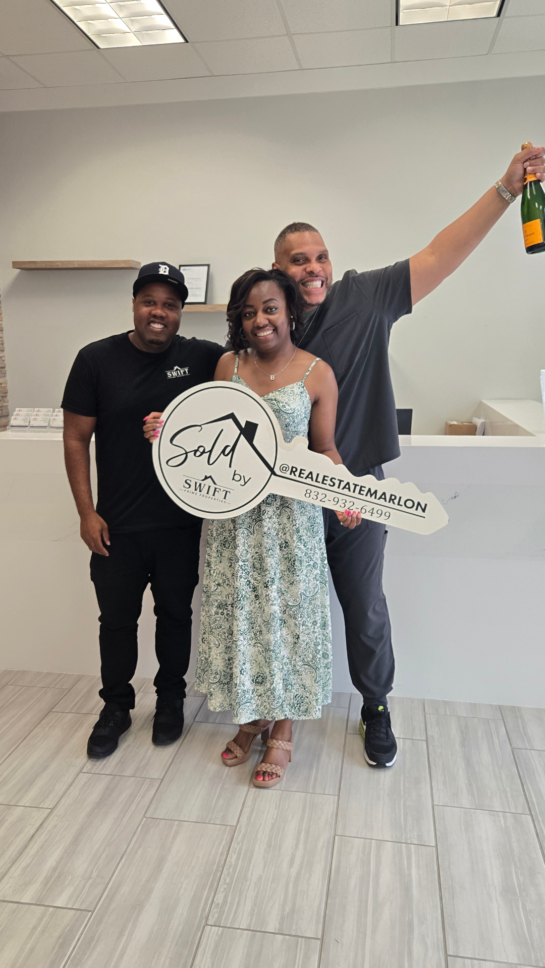 Marlon Wilson with two clients and a sold key sign during a closing celebration.
