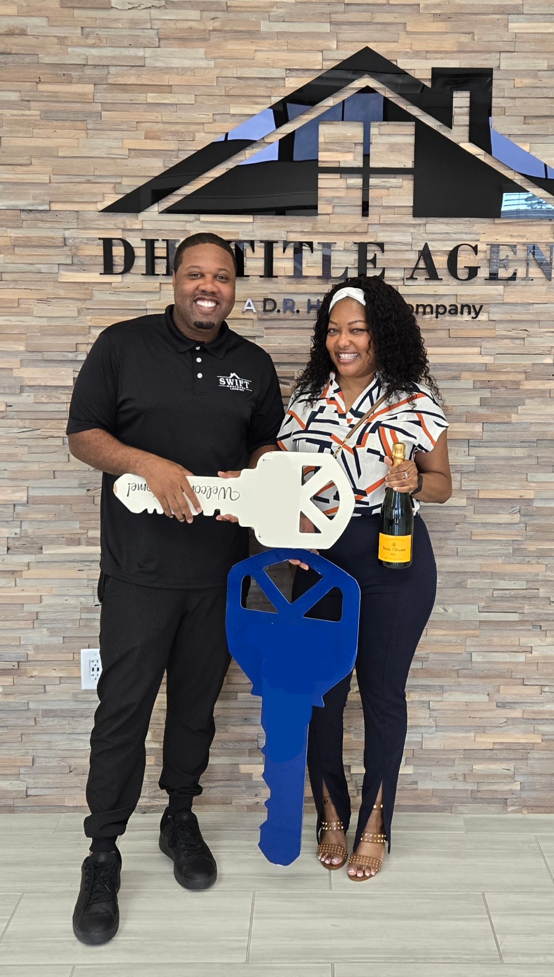 Marlon Wilson with a client holding oversized ceremonial keys at a closing office.